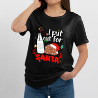 Black crewneck T-shirt worn in slight side view, “I put out for SANTA” milk & cookie print