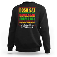Black crewneck sweatshirt with colorful 'Rosa Sat' and 'Celebrating' front graphic