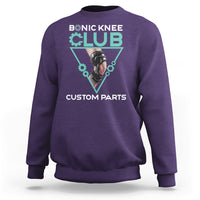 Purple crewneck sweatshirt with robotic knee graphic print in teal triangle.