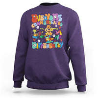 Purple crewneck sweatshirt with colorful “Be Different” graphic on chest