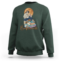 Forest green women’s sweatshirt with front “Booktrovert” graphic of reader and stacked books