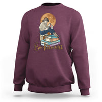 Maroon women’s sweatshirt with front “Booktrovert” graphic of reader and stacked books