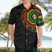 Mens black Hawaiian shirt with colorful circular emblem, patterned icons, and button collar