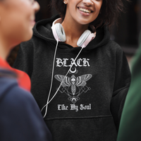 Charcoal hoodie with moth-and-skull graphic; woman wearing over-ear headphones.