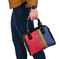 Red-blue handbag being carried by black top handles with long crossbody strap