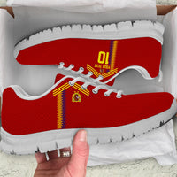 Red low-top sneakers with yellow-red stripe, white laces, textured knit upper