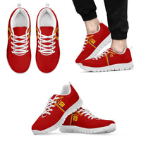 Red sneakers with yellow-red side stripe, white laces, worn with black pants