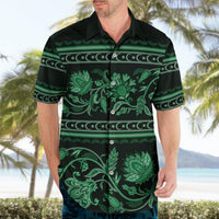 Green Hawaiian shirt on model, collared button-up with short sleeves and floral ornament print.