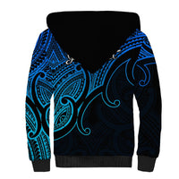 Sherpa hoodie with blue-and-black tribal graphic, dark hood and ribbed cuffs