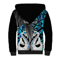 Sherpa hoodie with black back, blue Maori-style artwork and leaf detail, sherpa hood