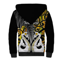 Black sherpa hoodie with back hood and large gold and green tiki-style fern and feather graphic