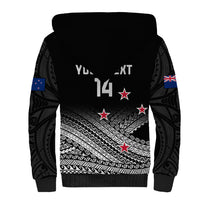 Black sherpa hoodie back with Maori fern tribal print, stars, and New Zealand flag sleeve patches