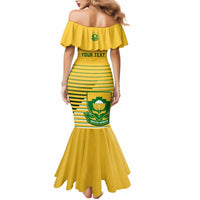 Yellow off-shoulder bodycon dress with green stripes, shield emblem, and flared hem