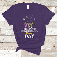 Purple T-shirt with colorful feather arrow graphic and “Columbus Indigenous People’s Day” text