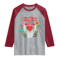 I Hear Migrant Children Also Have Heartbeats Raglan Shirt Groovy Retro Floral Hands Heart Social Justice