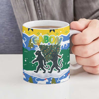 Gabon Christmas Ceramic Mug with Black Panthers Carrying Tree and Green Yellow Snowflake Pattern - Wonder Print Shop