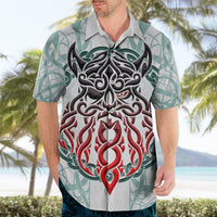 Light gray short-sleeve Hawaiian shirt worn by man, featuring teal pattern and red/black Odin print