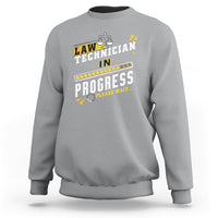 Light gray crewneck sweatshirt with filmstrip "In Progress" graphic and scales icon