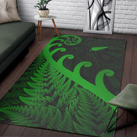 Green and dark area rug with large koru curve and fern leaf pattern; bordered corners.
