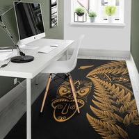 Black rug with gold tiki mask, geometric fern design, and border edges