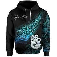 Black hoodie with teal-blue fern & manaia/matau fish print; front hood and drawstrings
