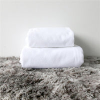 Folded white beach towel stacked on soft gray shag pile