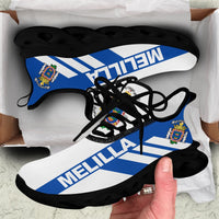 Black clunky sneakers with MELILLA stripe graphic, crest patches, black laces and sole