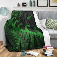 Green fern and koru blanket draped over sofa, light gray/white border edge visible