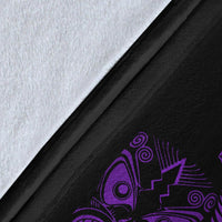 Close-up of black fleece blanket fabric with purple fern-and-mask artwork and white backing