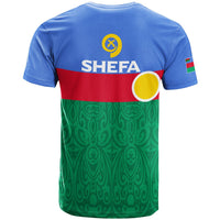 Light blue T-shirt, back shows Shefa text, yellow circle emblem and green patterned hem