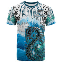 Blue graphic T-shirt with Maori-style pattern, fern leaves, and ocean waves print