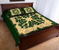 Green quilt and two cream accent pillows with dark-green leafy medallion and border