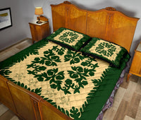 Green-and-cream quilt set with large leafy medallion, two matching square pillows on bed