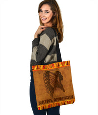 Brown tote bag with Native American text, black headdress silhouette, orange tribal top trim, strap