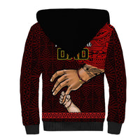 Back of black sherpa zip hoodie with red Tongan pattern sleeves and hand graphic