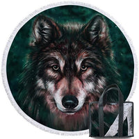 Round beach towel with wolf face graphic, dark teal background, with tote bag beside it