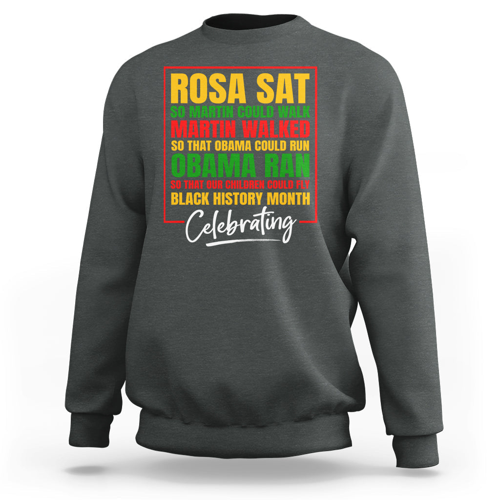 Dark heather gray crewneck sweatshirt with colorful 'Rosa Sat' and 'Celebrating' front graphic