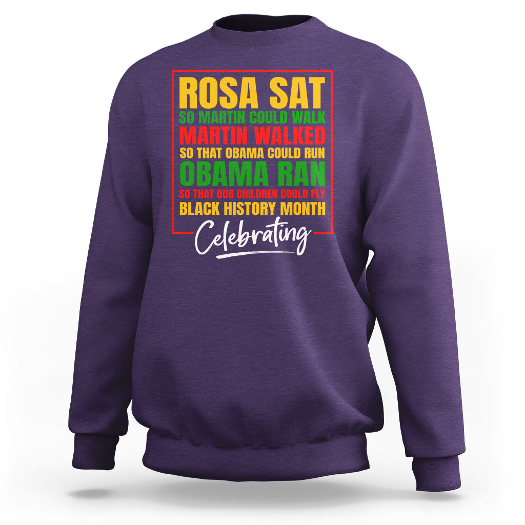 Purple crewneck sweatshirt with colorful 'Rosa Sat' and 'Celebrating' front graphic