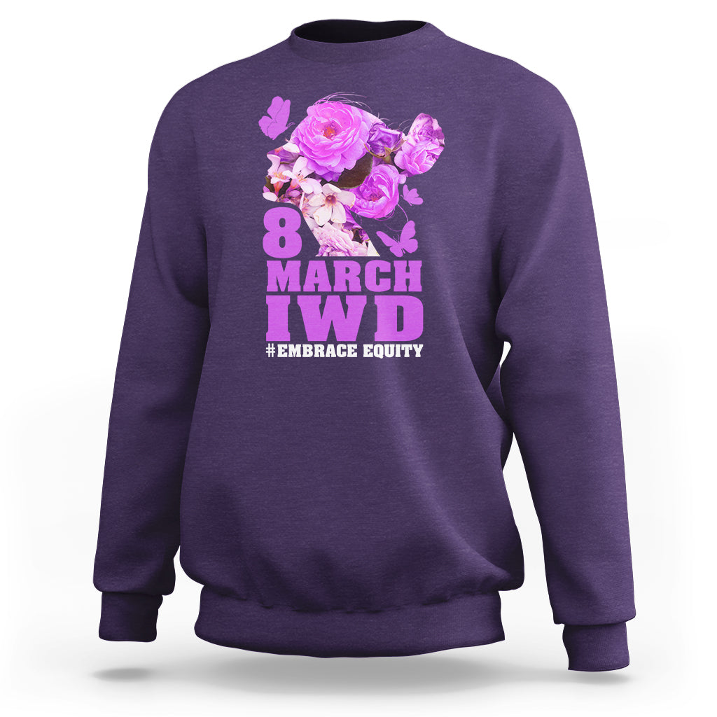 Purple women’s sweatshirt with floral IWD graphic and text #EMBRACE EQUITY on front