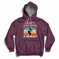 Maroon maternity pullover hoodie with kangaroo pocket and drawstring hood; busy human graphic