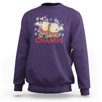 Women's purple sweatshirt with colorful butterfly and “Be Bold for Change” graphic on front