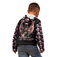 Child wearing black hoodie with hood up, angel skull back print, pink rose-and-skull sleeve pattern.