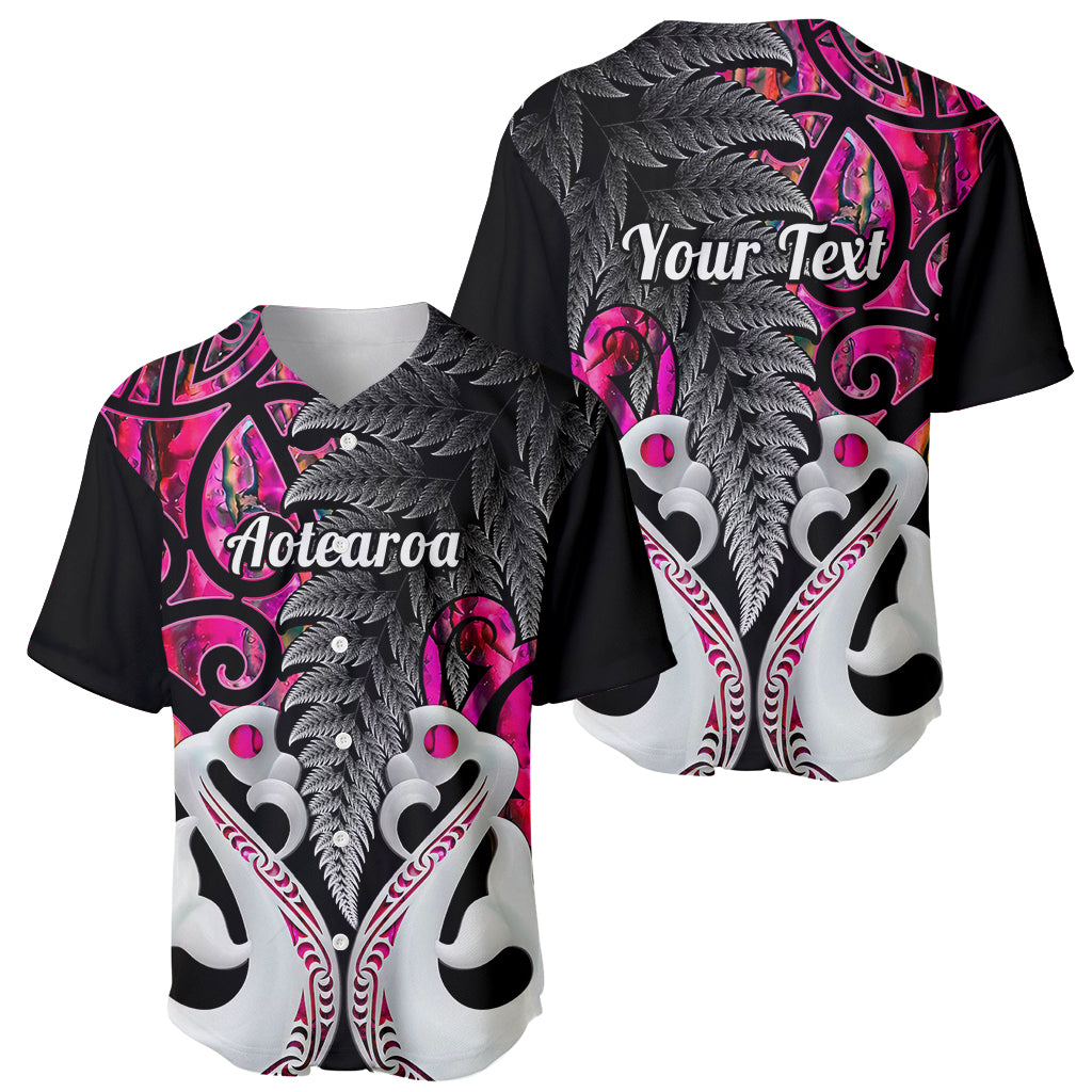 Two baseball jersey views in pink and black with fern and Maori-style crest artwork