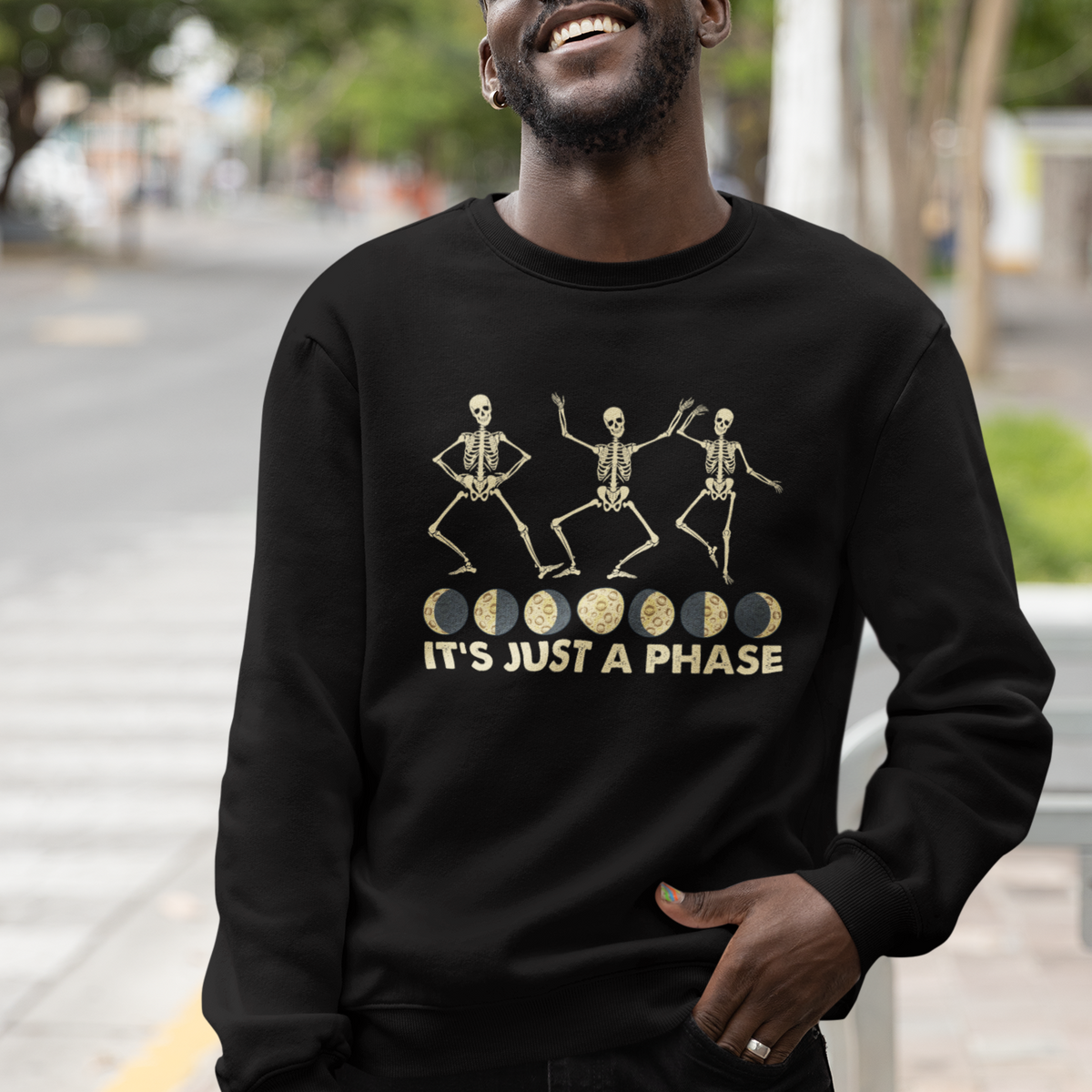 Black crewneck sweatshirt worn by a person with dancing skeleton graphic and slogan