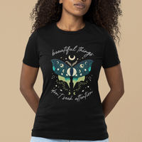 Women’s black T-shirt with teal moth graphic, crescent moons, and “beautiful things” text