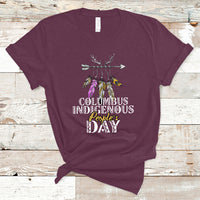 Maroon T-shirt with colorful feather arrow graphic and “Columbus Indigenous People’s Day” text