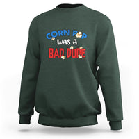 Dark forest green sweatshirt with “Corn Pop was a bad dude” graphic on the front