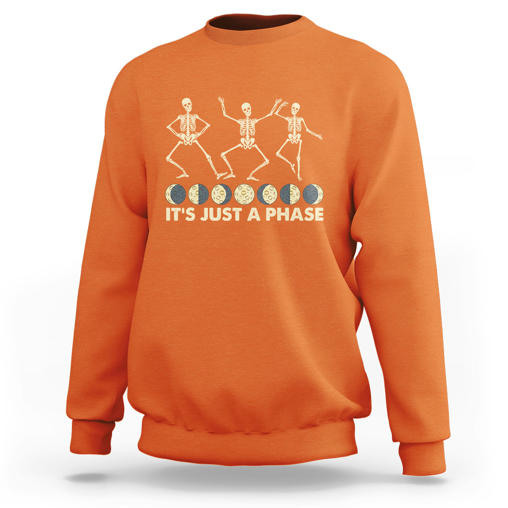 Orange crewneck sweatshirt with dancing skeleton graphic and “IT’S JUST A PHASE” text