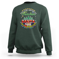 Dark forest green teacher sweatshirt with colorful Santa-watching holiday graphic on chest.