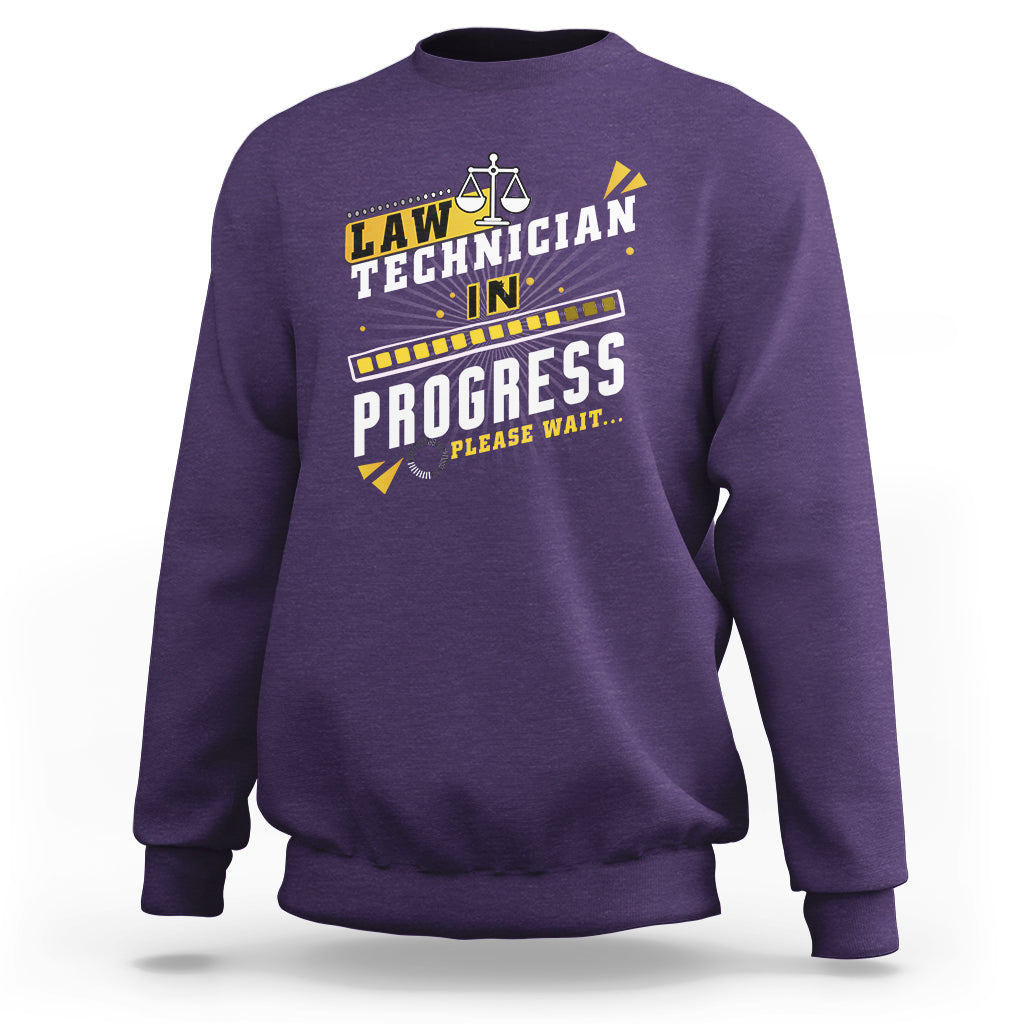 Purple crewneck sweatshirt with filmstrip "In Progress" graphic and scales icon